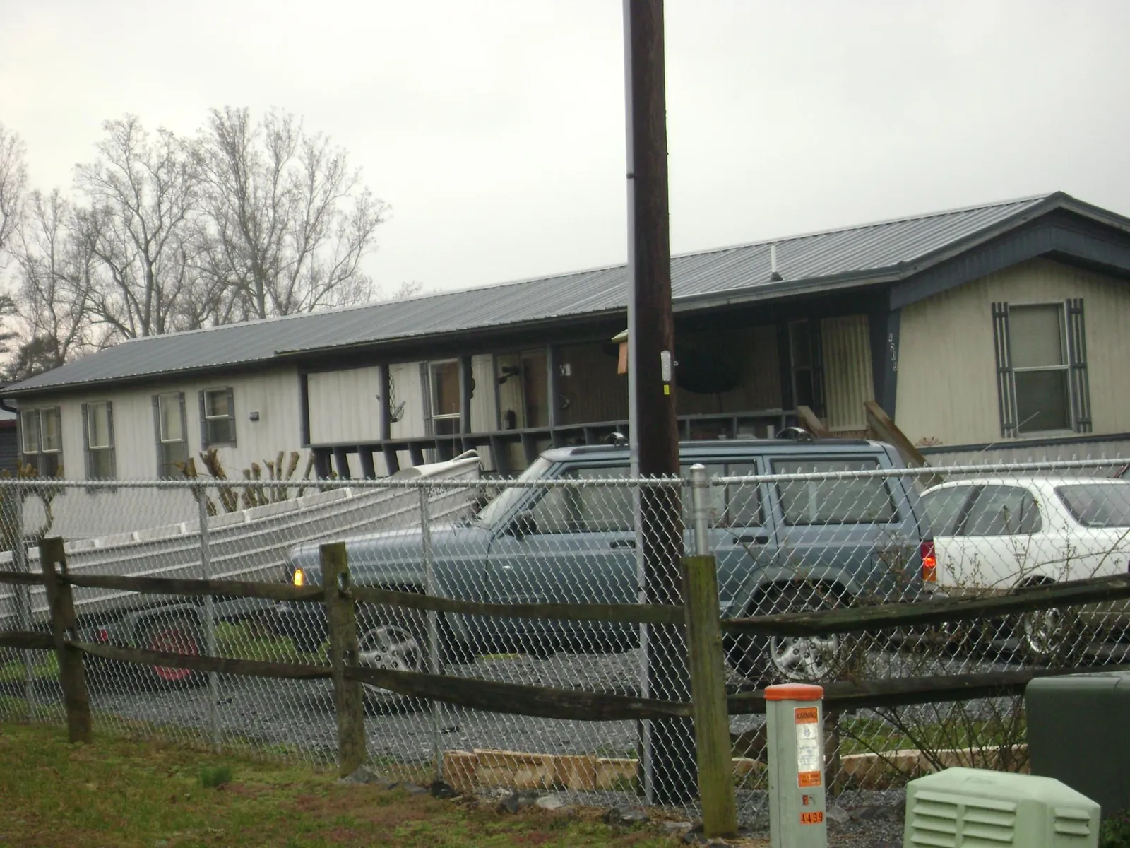 Dark metal roof on a long single story building behind a chain link fence in Rutland