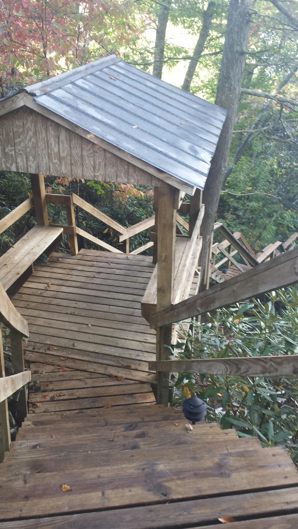 Metal roofed shelter over wooden steps on a wooded walkway — Skylight Repair & Installation work by our crew in Rutland