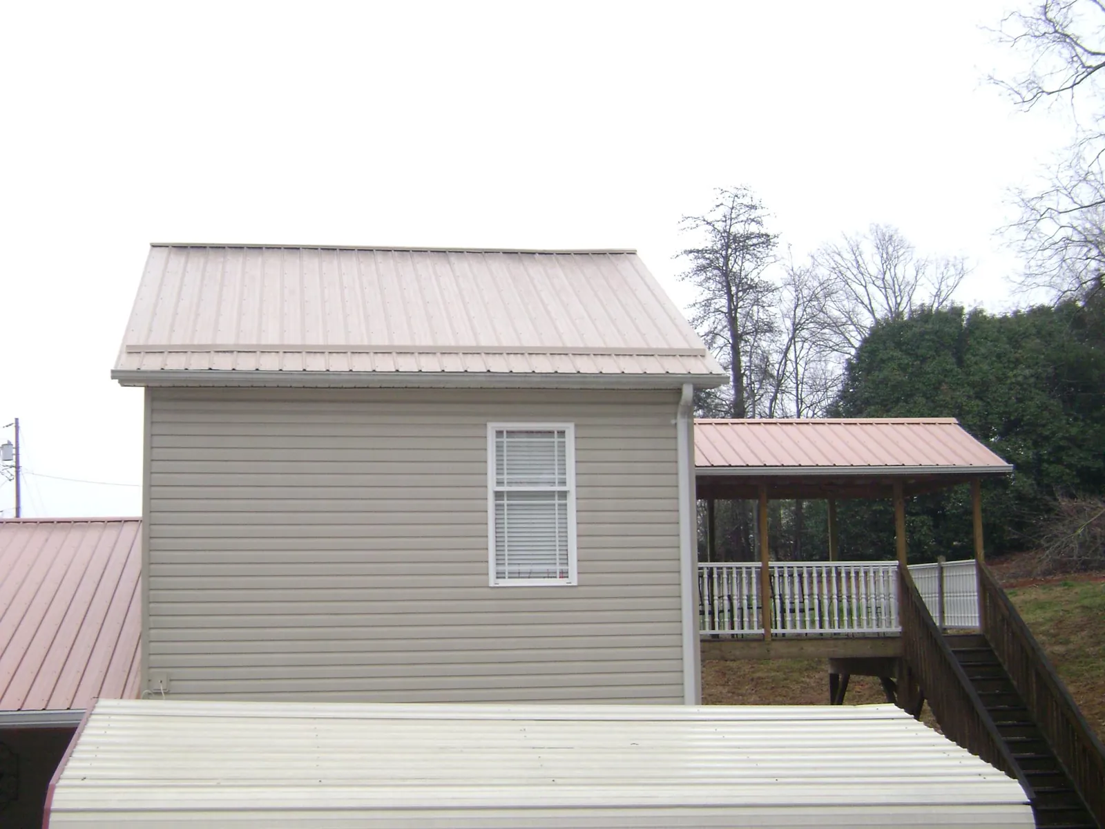 Tan metal roofs on a two story addition and attached porch, from a Roof Replacement job in Rutland